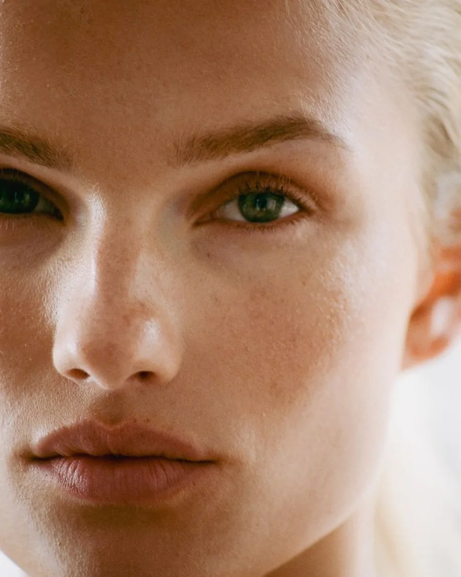 Extreme close-up of a woman's green eyes and dewy skin