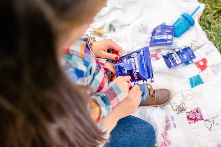 A child holding Begin Health packets on a blanket outdoors.