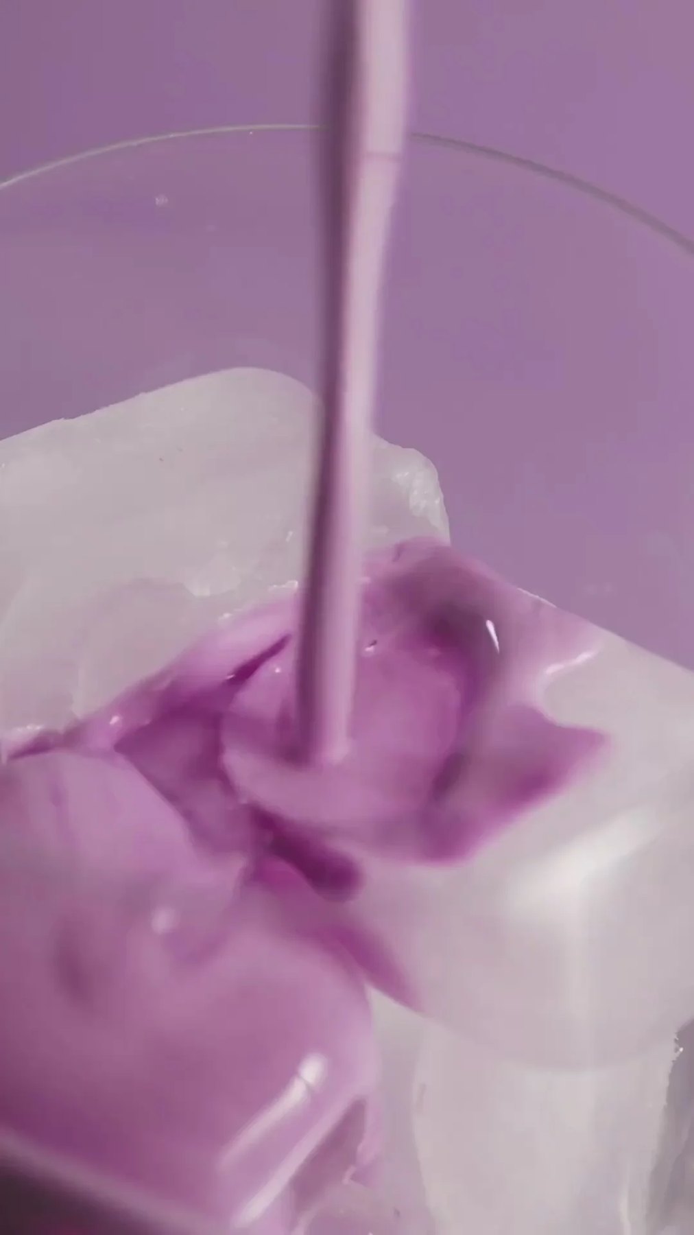 Purple collagen drink being poured over ice in a glass.