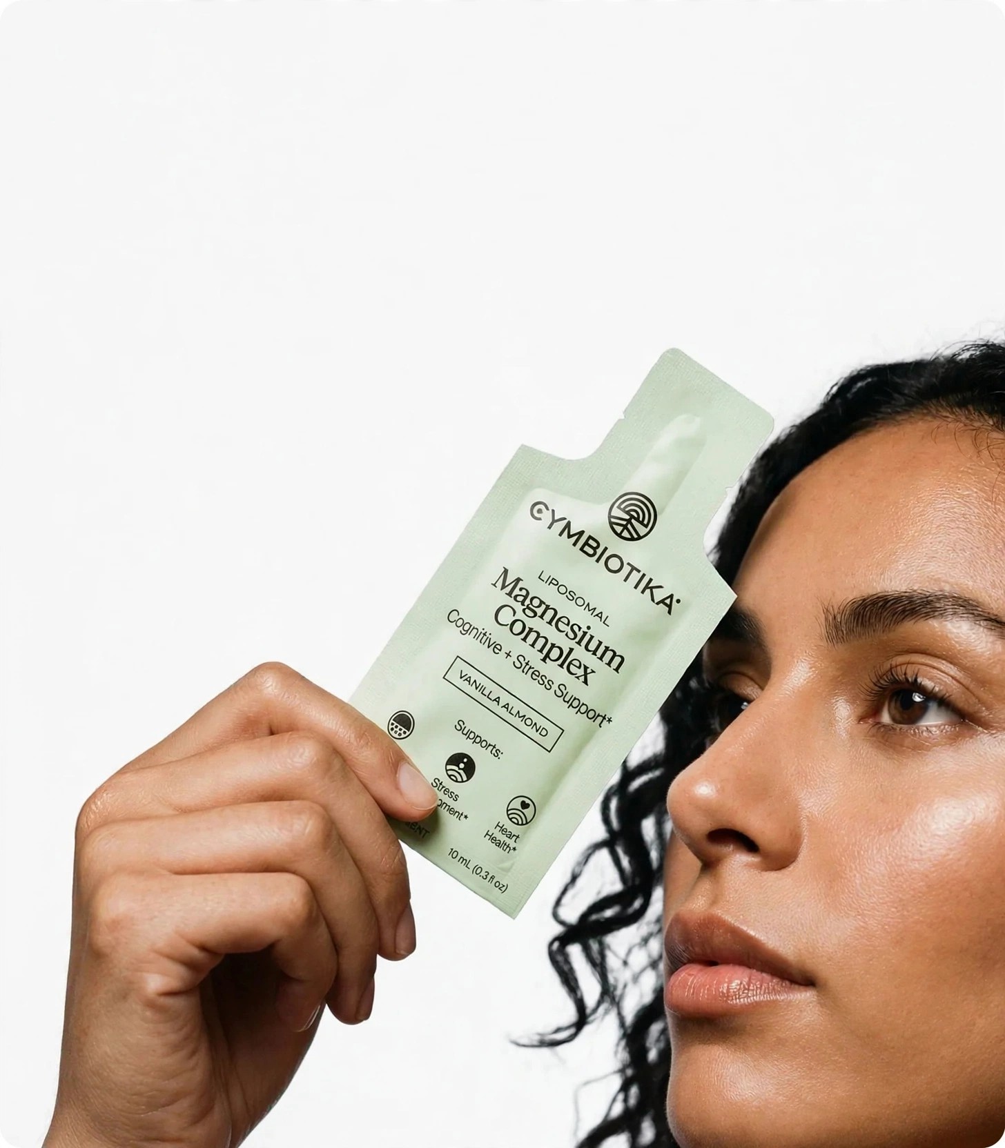 Woman holding a Cymbiotika liposomal pouch beside her face.