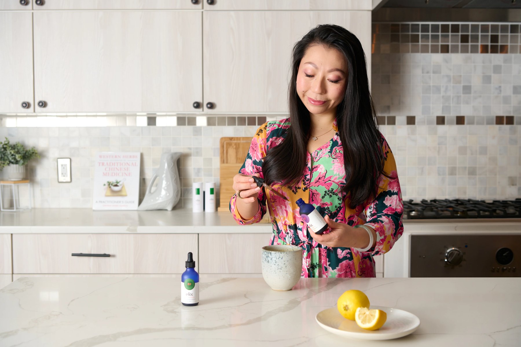 Lulu Ge adds Elix liquid drops to a mug in kitchen.