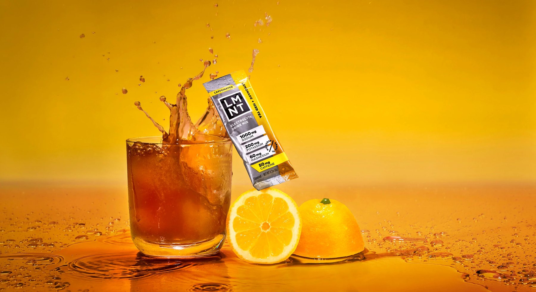 LMNT electrolyte packet with splashing iced tea and lemons on yellow.