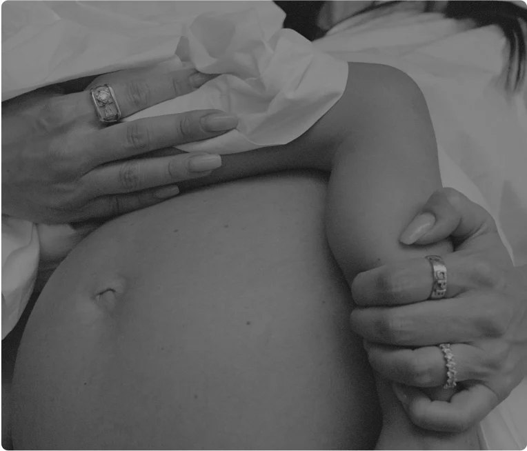 Hands cradling a pregnant belly in black and white.