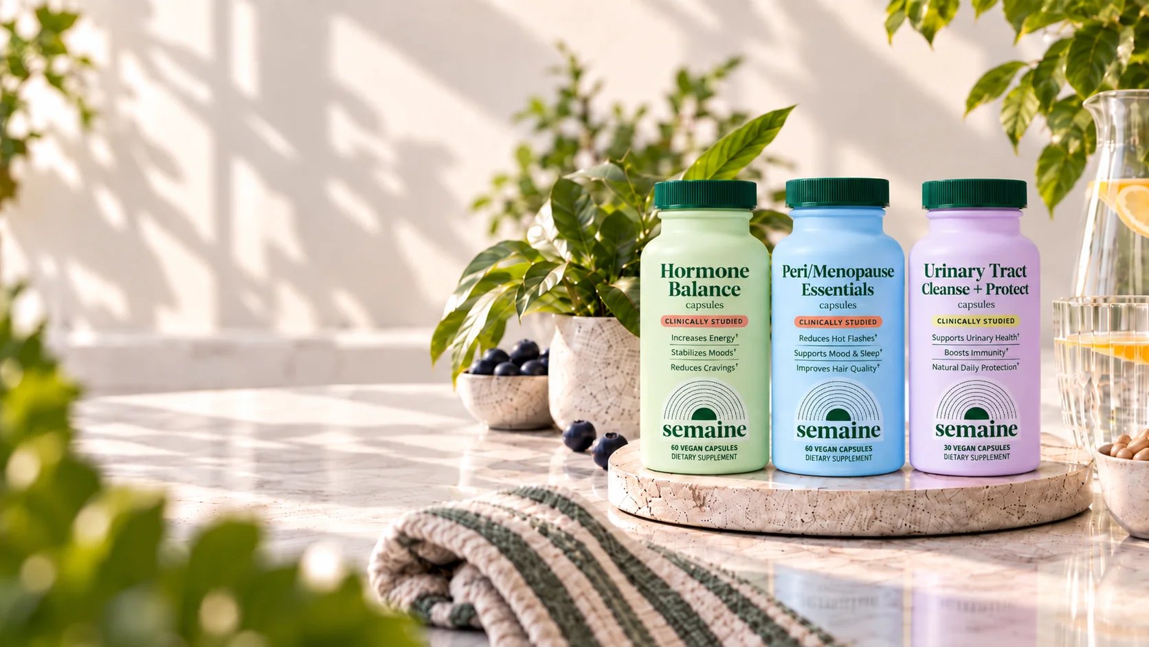 Three Semaine bottles on a marble counter with plants.