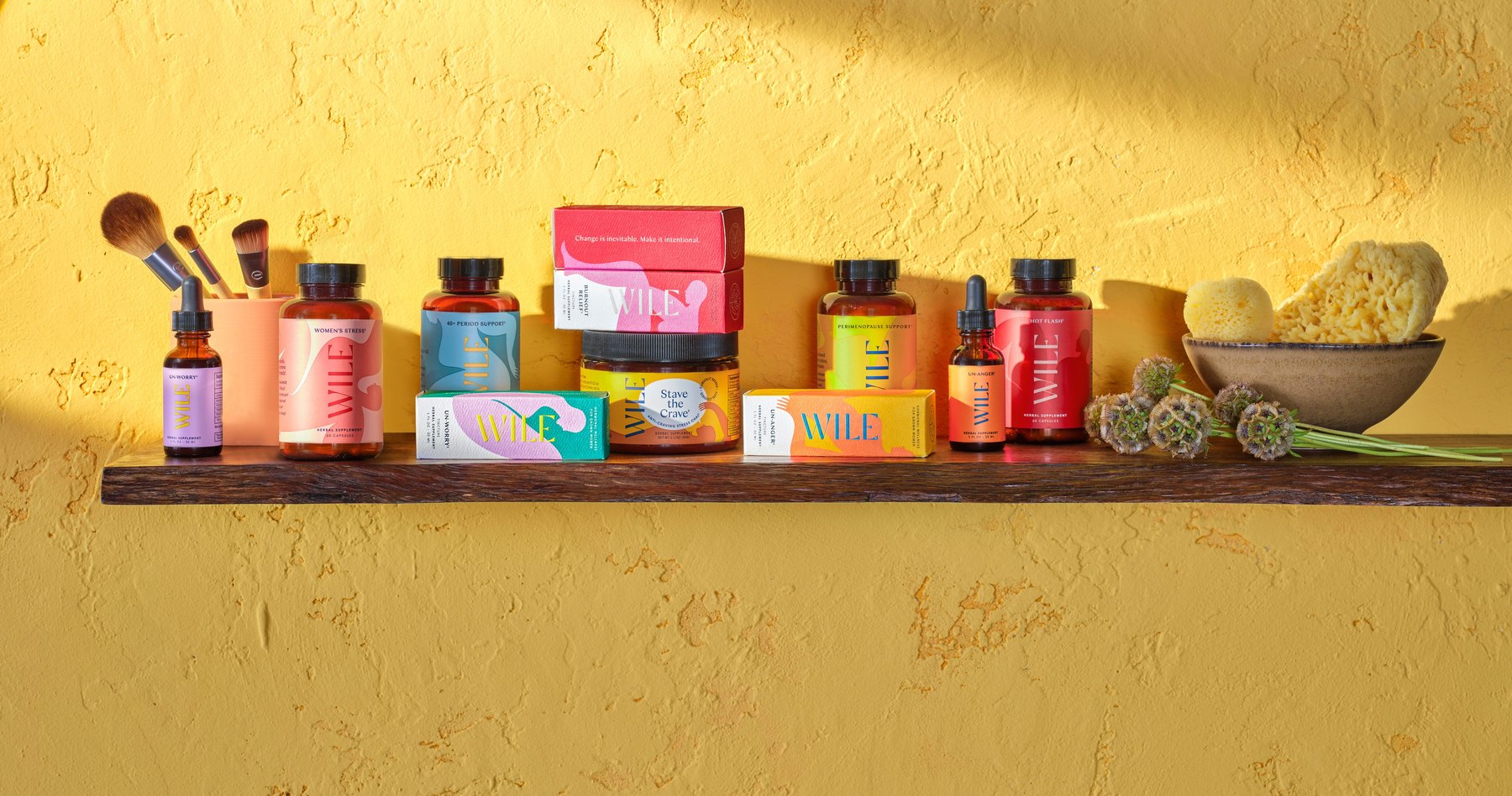Assorted Wile products displayed on wooden shelf against yellow wall.